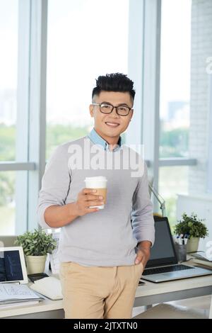 Porträt eines jungen Geschäftsmannes in einer Brille, der im Büro Kaffee trinkt Stockfoto