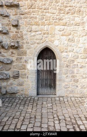 Mittelalterliche Burg Holztür, Steinmauer und Kopfsteinpflasterboden, verical Format Stockfoto