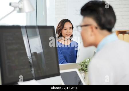 Junge Geschäftsfrau, die an ihrem Arbeitsplatz vor ihrer Kollegin arbeitet Stockfoto