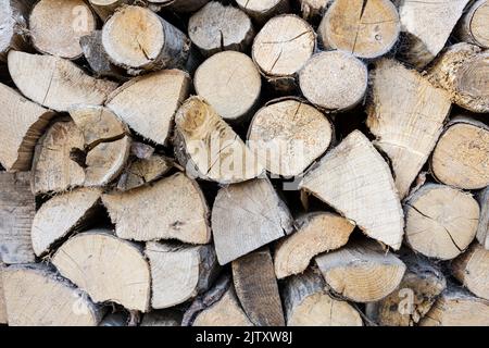 Gehackte und trockene Holzstämme, die in den Wintermonaten als Brennstoff für einen Holzbrenner gelagert und einsatzbereit sind Stockfoto