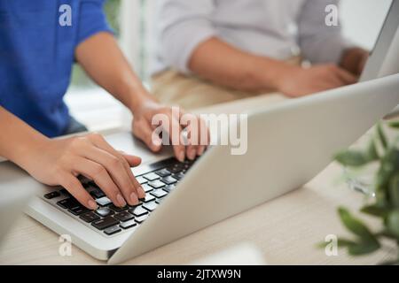 Nahaufnahme einer Geschäftsfrau, die am Arbeitsplatz auf dem Laptop tippt Stockfoto