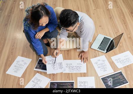 Junge Geschäftsleute, die gemeinsam mit der Unternehmensstrategie am Boden arbeiten Stockfoto