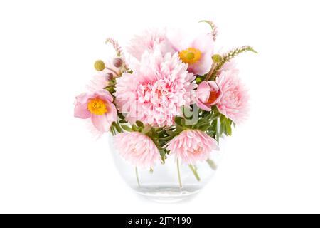 Anmutiger Herbststrauß aus rosa Asterblüten, Anemonen in runder Glasvase isoliert auf weißem Hintergrund Stockfoto