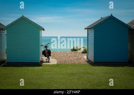 Altes Fahrrad, das an einem Sommertag in Littlehampton, West Sussex, an Strandhütten angelehnt ist Stockfoto