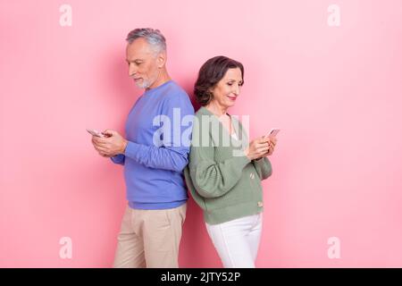 Foto von zwei älteren Menschen verwenden Telefon chatten SMS Kommentar isoliert auf rosa Hintergrund Stockfoto