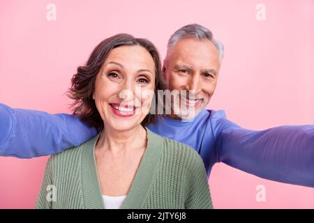 Foto von zwei fröhlichen nett gealterten Partnern machen Selfie toothy Lächeln isoliert auf rosa Hintergrund Stockfoto