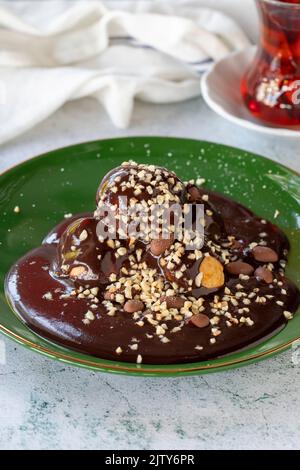 Profiterole. Schokolade proliteroles Dessert auf Teller auf grauem Hintergrund. Nahaufnahme Stockfoto