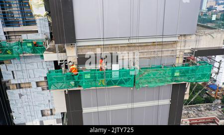 Hängende Plattform, Bauaufhängung am Gebäude. Installations- und Reparaturarbeiten. Gebäude Fassaden Bauarbeiten. Glasfassade von hoch Stockfoto