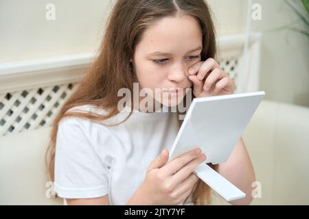 Portrait eines Mädchens, das den Spiegel hält und Akne anschaut Stockfoto