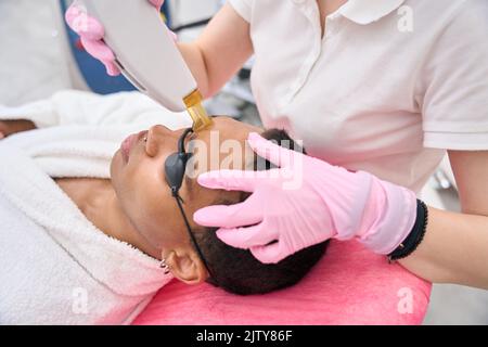 Schönheitssalon-Kunde wird einem Laser-Epilierverfahren unterzogen Stockfoto