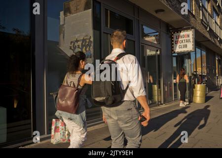 Junge Leute, die am frühen Abend einen Drink im Club in Shoreditch, London, England, Großbritannien, genießen möchten Stockfoto