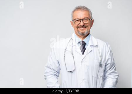 Horizontales Porträt eines ernsten reifen männlichen Arztes oder Therapeuten in weißer medizinischer Uniform, Brille und Stethoskop, reifer alter Mann GP oder Arzt in Stockfoto
