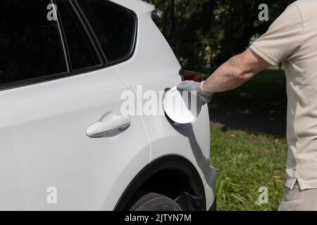 Der Mann öffnet die Luke des Gastanks des Autos Stockfoto