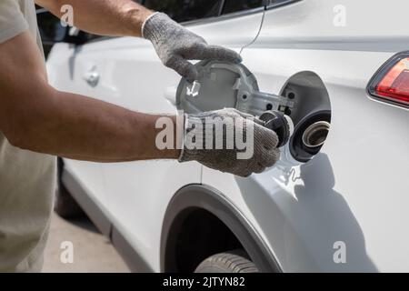 Der Mann öffnet die Luke des Gastanks des Autos Stockfoto