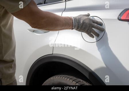 Der Mann schließt die Luke des Gastanks des Autos Stockfoto