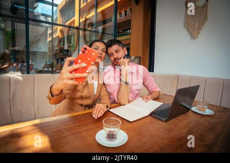 Junge Geschäftsleute machen ein Selfie, nachdem sie erfolgreich das Problem ihres Projekts gelöst haben Stockfoto