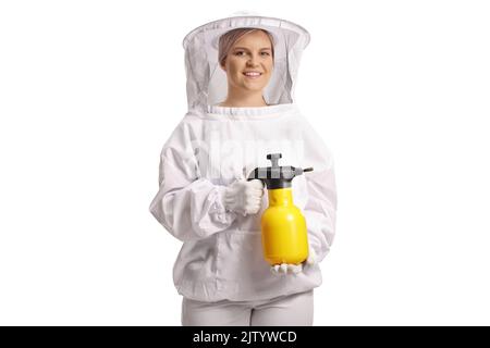 Junge Bienenhalterin in einer Uniform, die eine Flasche hält, um isoliert auf blauem Hintergrund zu sprühen Stockfoto