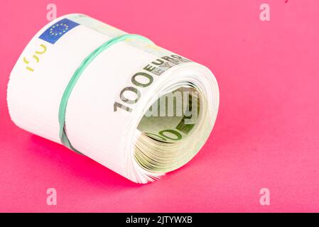 Gerolltes Paket von hundert Euro-Banknoten, gebunden mit einem Gummiband. Speicherplatz kopieren. Stockfoto