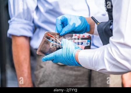 London, Großbritannien. 2. September 2022. Ein Polizeibeamter durchsucht die Brieftasche eines Klimaaktivisten, der sich an die Geländer vor den Toren der Houses of Parliament gebunden hatte. Frühere Klimaaktivisten hatten sich während einer Führung durch das Parlament, die sich in einer Sommerpause befand, um den Vorsitzenden des Sprechers im Unterhaus zusammengeklebt. Kredit: amer ghazzal/Alamy Live Nachrichten Stockfoto