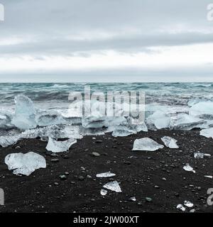 Eisbrocken brachen vom Gletscher ab, schweben ins Meer und waschen sich dann auf dem schwarzen Sand des Diamond Beach in Jökulsárlón, der Südküste Islands. Stockfoto
