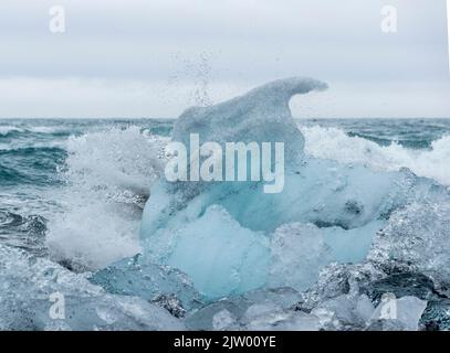 Eisbrocken brachen vom Gletscher ab, schweben ins Meer und waschen sich dann auf dem schwarzen Sand des Diamond Beach in Jökulsárlón, der Südküste Islands. Stockfoto
