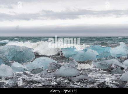 Eisbrocken brachen vom Gletscher ab, schweben ins Meer und waschen sich dann auf dem schwarzen Sand des Diamond Beach in Jökulsárlón, der Südküste Islands. Stockfoto