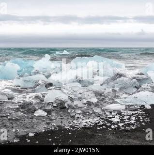 Eisbrocken brachen vom Gletscher ab, schweben ins Meer und waschen sich dann auf dem schwarzen Sand des Diamond Beach in Jökulsárlón, der Südküste Islands. Stockfoto