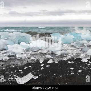 Eisbrocken brachen vom Gletscher ab, schweben ins Meer und waschen sich dann auf dem schwarzen Sand des Diamond Beach in Jökulsárlón, der Südküste Islands. Stockfoto