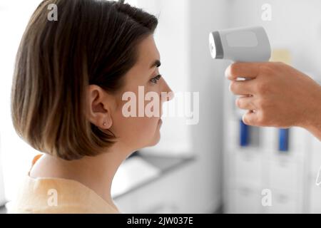 Arzt mit Thermometer und Frau im Krankenhaus Stockfoto