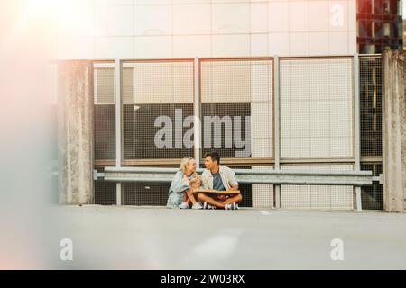 Ein glückliches Paar, das auf dem Parkplatz auf dem Dach der Stadt Pizza gegessen hat Stockfoto