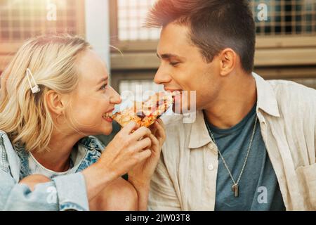Glückliches Paar, das im Freien Pizza isst Stockfoto