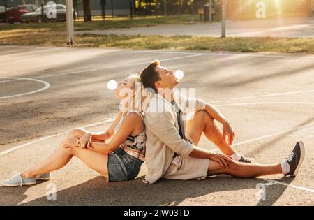 Pärchen sitzt auf dem Boden und bläst Blasengummis Stockfoto