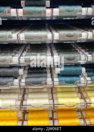 Nähfäden mehrfarbigen Hintergrund. Bunte Garnspulen, die in der Stoff- und Textilindustrie verwendet werden. Vertikales Foto Stockfoto