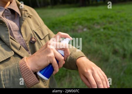Frau, die im Park Insektenschutzmittel zur Hand sprüht Stockfoto