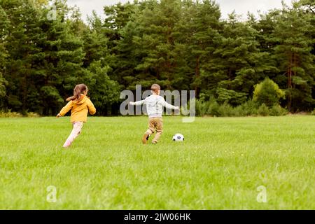 Kleine Kinder mit Ball spielen Fußball im Park Stockfoto