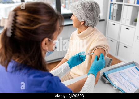 Krankenschwester mit Spritze, die der Frau Injektion macht Stockfoto