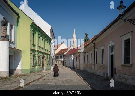 Mönch auf einer Straße in Bratislava Altstadt mit Clarissine Kirchturm im Hintergrund - Bratislava, Slowakei Stockfoto