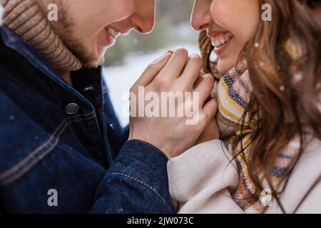 Glücklicher Mann, der die Hände der Frau im Winterpark wärmte Stockfoto