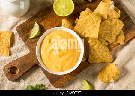 Hausgemachter Yellow Queso Käse Dip mit Tortilla Chips und Limette Stockfoto