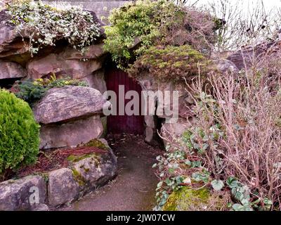 Versteckte Tür in Felsen mit überwucherten Pflanzen Stockfoto