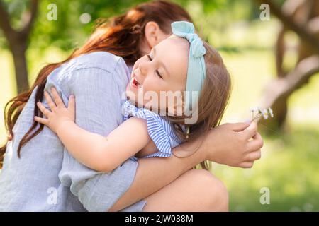 Glückliche Mutter und Tochter mit Blumen im Park Stockfoto