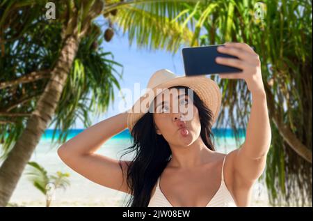 Lächelnde Frau im Bikini beim Selfie am Strand Stockfoto