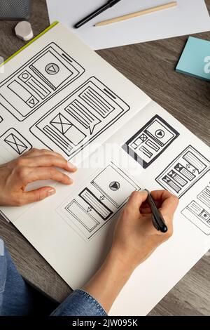 UI Designer skizziert die Benutzeroberfläche einer Webanwendung für ein Mobiltelefon. Ein Entwickler erstellt einen Prototyp für ein Smartphone. Stockfoto