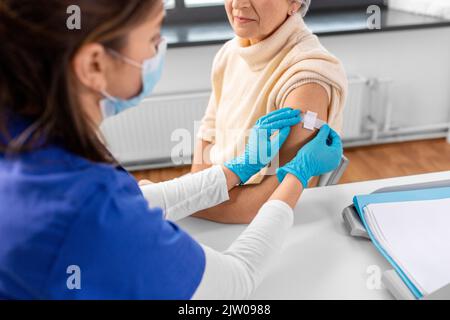 Krankenschwester, die eine geimpfte Frau mit einem medizinischen Pflaster bewirbt Stockfoto