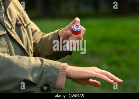 Frau, die im Park Insektenschutzmittel zur Hand sprüht Stockfoto