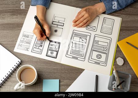 UI Designer skizziert die Benutzeroberfläche einer Webanwendung für ein Mobiltelefon. Ein Entwickler erstellt einen Prototyp für ein Smartphone. Stockfoto