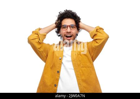 Glücklicher lächelnder Mann in einer Brille, der sich am Kopf hält Stockfoto