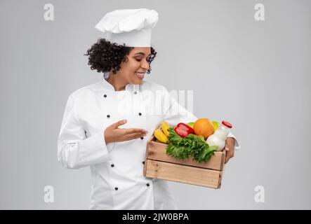 Glückliche lächelnde Köchin mit Essen in Holzkiste Stockfoto