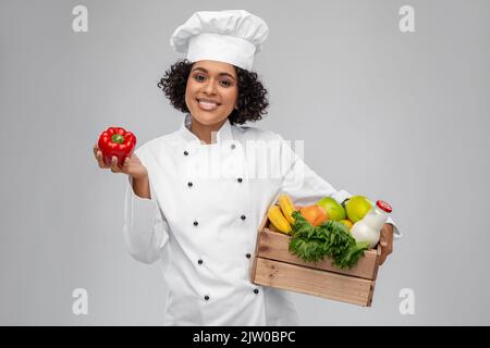 Glückliche lächelnde Köchin mit Essen in Holzkiste Stockfoto