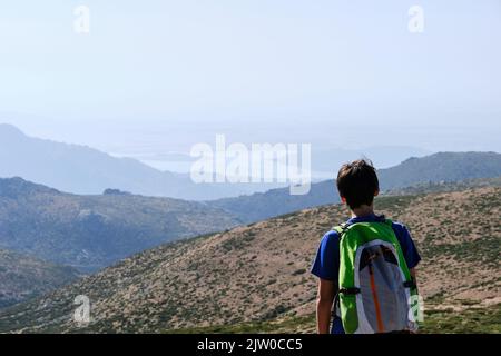 Teenager mit Rucksack, der im Sommer die Berge bewundert Stockfoto